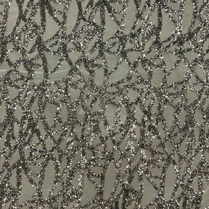 May include: Silver glitter fabric with a geometric pattern on a sheer mesh background.