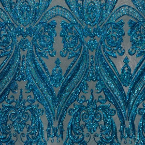 Puede incluir: Paillettes iridiscentes azul turquesa sobre una tela de malla con un patr&oacute;n de damasco.