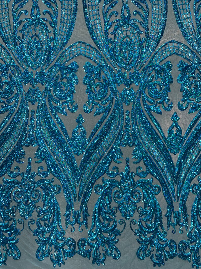 Puede incluir: Paillettes iridiscentes azul turquesa sobre una tela de malla con un patr&oacute;n de damasco.