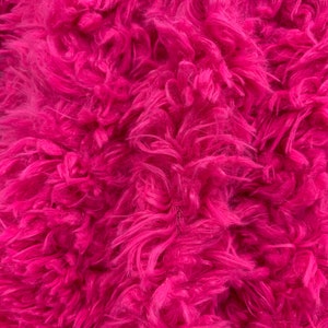 May include: Close-up of a bright pink fluffy fabric. The texture is soft and fuzzy.