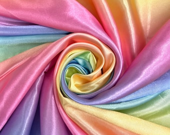 May include: A close-up of a rainbow-colored satin fabric, with the colors transitioning from pink to yellow. The fabric is arranged in a spiral pattern, creating a swirling effect.