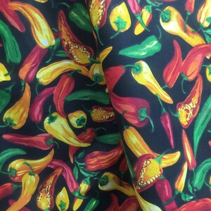 May include: A black fabric with a repeating pattern of red, yellow, and green chili peppers. The peppers are in various sizes and orientations.