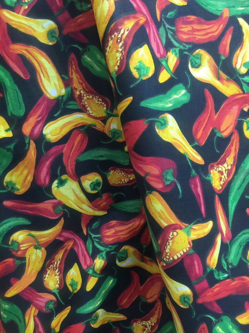 May include: A black fabric with a repeating pattern of red, yellow, and green chili peppers. The peppers are in various sizes and orientations.