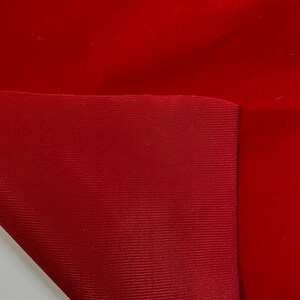 Puede incluir: Primer plano de dos piezas de tela, una de terciopelo rojo y otra de tela tejida roja. La tela de terciopelo est&aacute; doblada sobre la tela tejida.