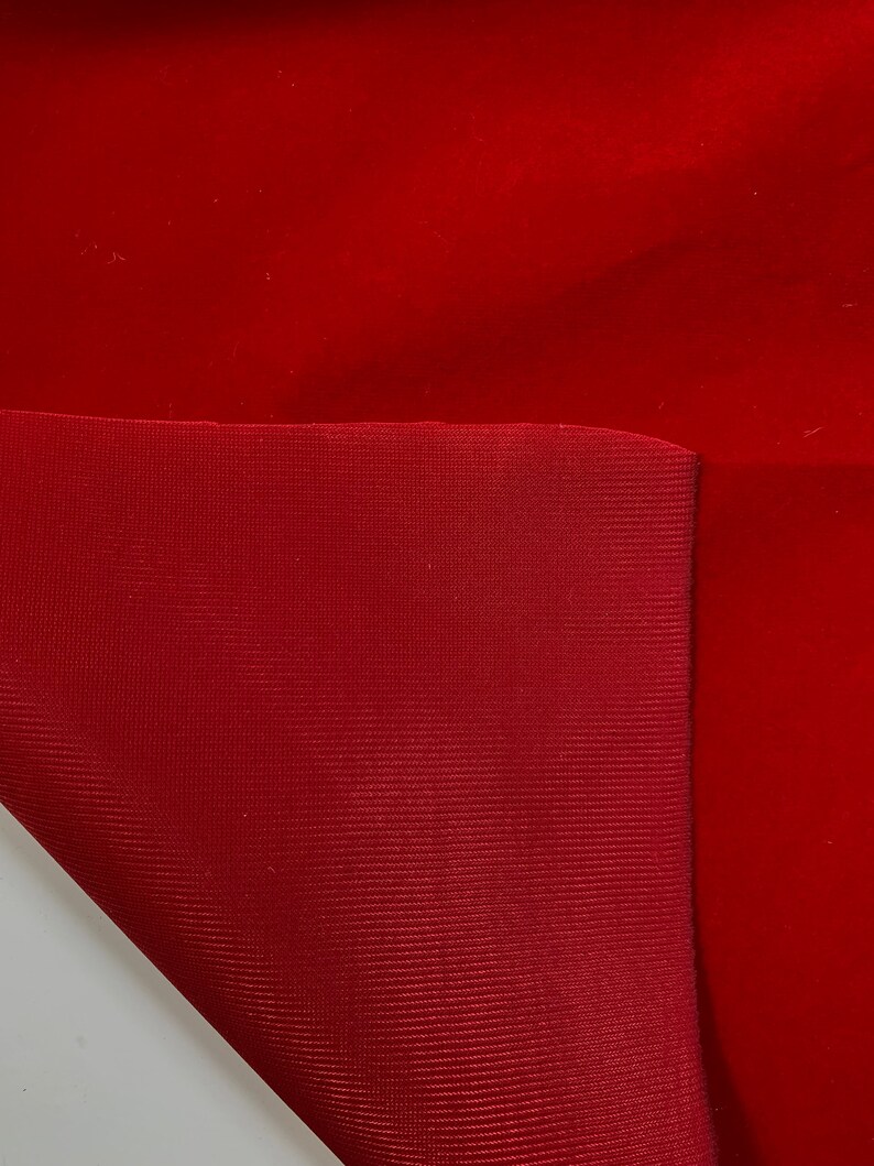 Puede incluir: Primer plano de dos piezas de tela, una de terciopelo rojo y otra de tela tejida roja. La tela de terciopelo est&aacute; doblada sobre la tela tejida.