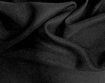 Puede incluir: Primer plano de una tela negra con textura visible y pliegues. El material parece suave y se drapea de forma natural, creando sombras y reflejos en su superficie. El color oscuro sugiere un posible uso para ropa o decoración del hogar.