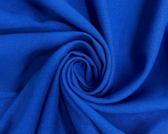 Puede incluir: Primer plano de una tela azul vibrante, doblada y retorcida en forma de espiral. La tela tiene una superficie texturizada, creando un patrón visualmente interesante.