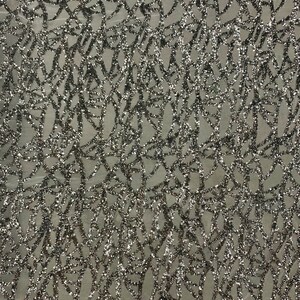 May include: Silver glitter fabric with a geometric pattern. The fabric has a mesh backing.