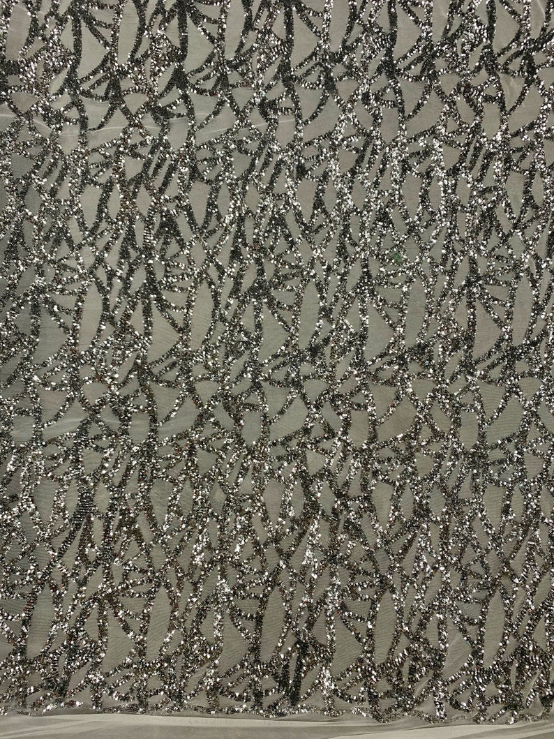 May include: Silver glitter fabric with a geometric pattern. The fabric has a mesh backing.