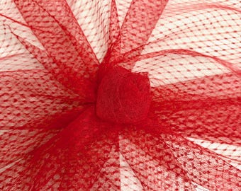 May include: Close-up of red netting fabric with a small, gathered rosette. The netting has a delicate, dotted pattern and is bunched up in the center. The fabric is a vibrant shade of red.