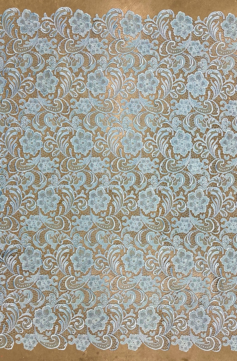 May include: A light blue lace fabric with a floral pattern. The fabric has a delicate, intricate design with small flowers and leaves.