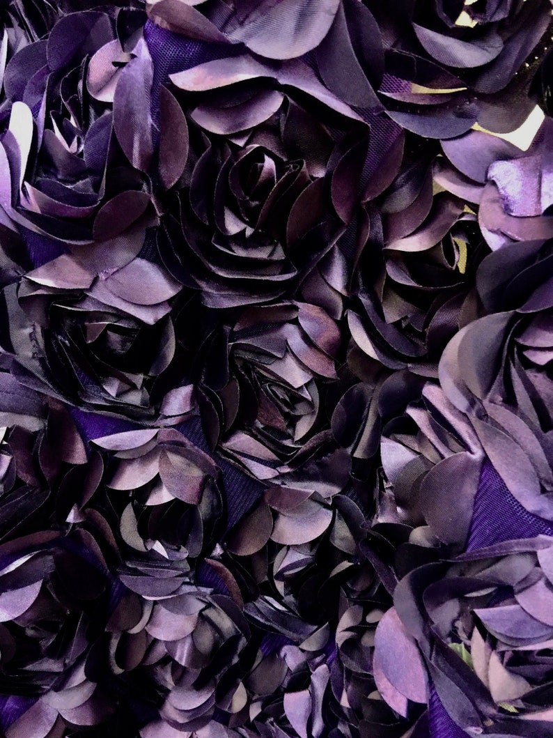 May include: Close-up of a fabric with a purple, 3D floral design. The fabric is made of many layers of petals, creating a textured and dimensional look.