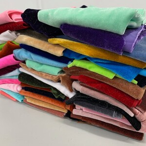K&ouml;nnte beinhalten: Ein Stapel bunter Samtstoffmuster in verschiedenen Farbt&ouml;nen von Rosa, Blau, Gr&uuml;n, Gelb, Orange, Rot, Braun und Schwarz.