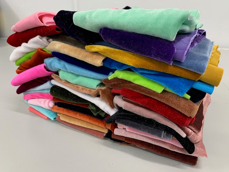 K&ouml;nnte beinhalten: Ein Stapel bunter Samtstoffmuster in verschiedenen Farbt&ouml;nen von Rosa, Blau, Gr&uuml;n, Gelb, Orange, Rot, Braun und Schwarz.
