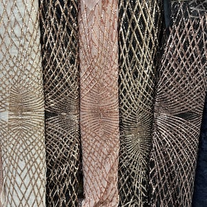May include: Five rolls of gold and rose gold sequined fabric with a geometric pattern. The fabric is on a black background.