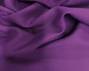 Puede incluir: Primer plano de una tela morada vibrante con pliegues suaves y textura sutil. El material parece ser un textil liso y tejido, posiblemente adecuado para proyectos de ropa o decoración del hogar. El color es un tono rico y saturado.