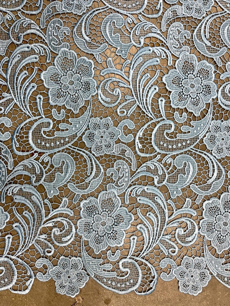 May include: Light blue lace fabric with a delicate floral pattern. The lace features intricate details and a soft, airy texture.