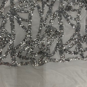 May include: Silver sequined fabric with a geometric pattern on a white mesh background.