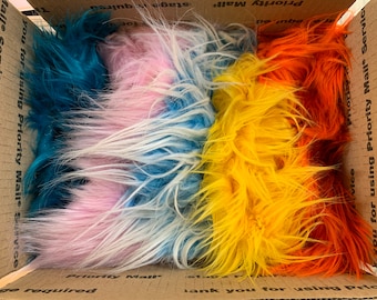 May include: A cardboard box filled with four bundles of faux fur in different colors: teal, pink, white, yellow, and orange.