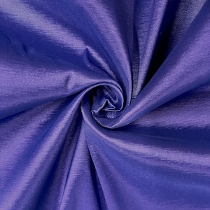 May include: A close-up of a smooth, silky fabric in a deep blue color. The fabric is folded and draped, showcasing its texture and sheen.
