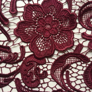 May include: Burgundy lace fabric with a delicate floral pattern. The lace is intricate and detailed, with a fine mesh background.