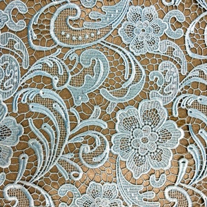 May include: Light blue lace fabric with a delicate floral pattern. The lace features intricate swirls and flowers.