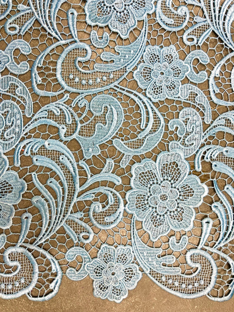 May include: Light blue lace fabric with a delicate floral pattern. The lace features intricate swirls and flowers.