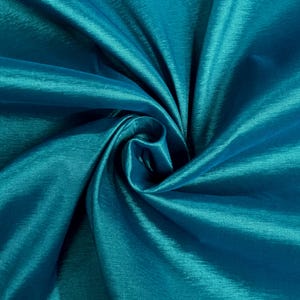 May include: Teal satin fabric with a smooth, silky texture. The fabric is folded and draped, creating a soft, flowing look.