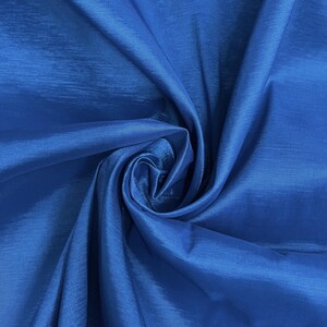 May include: A close-up of a vibrant blue fabric with a silky sheen. The fabric is folded and draped, showcasing its smooth texture and subtle sheen.