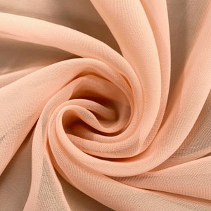 May include: Peach colored sheer fabric with a soft, flowing texture. The fabric is draped and folded, creating a swirl pattern.