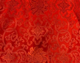 Könnte beinhalten: Roter Stoff mit einem sich wiederholenden Muster aus komplizierten floralen Designs. Der Stoff hat einen dezenten Glanz und eine strukturierte Oberfläche.