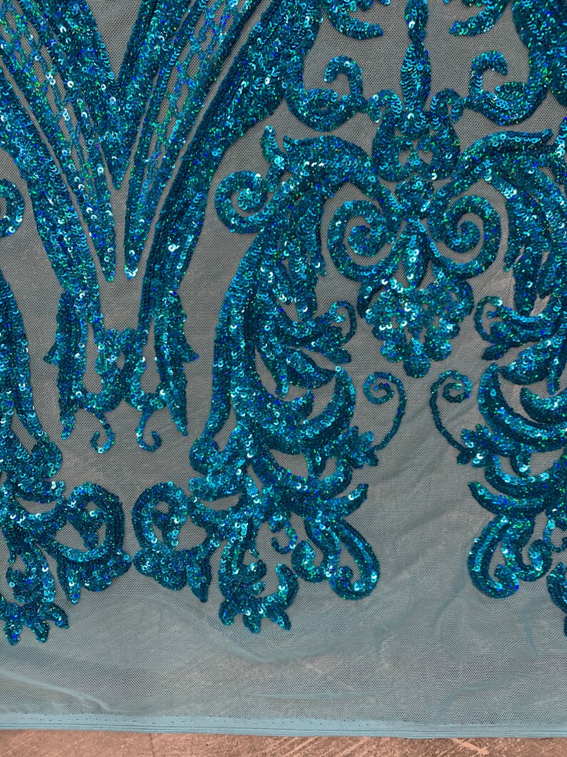 Puede incluir: Tela de lentejuelas azul turquesa con un patr&oacute;n floral sobre un fondo de malla azul claro.