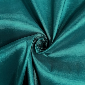 May include: Teal satin fabric with a smooth, silky texture. The fabric is folded and draped, creating a soft, flowing look.