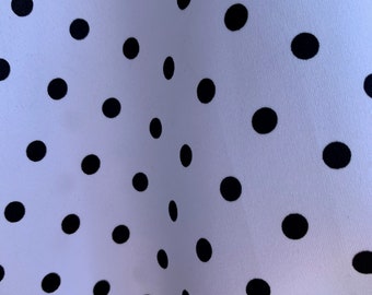 May include: White fabric with a black polka dot pattern. The fabric is folded in half, creating a diagonal line.
