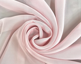 May include: A soft, pink fabric with a delicate, flowing texture. The fabric is draped and twisted, creating a swirling pattern.