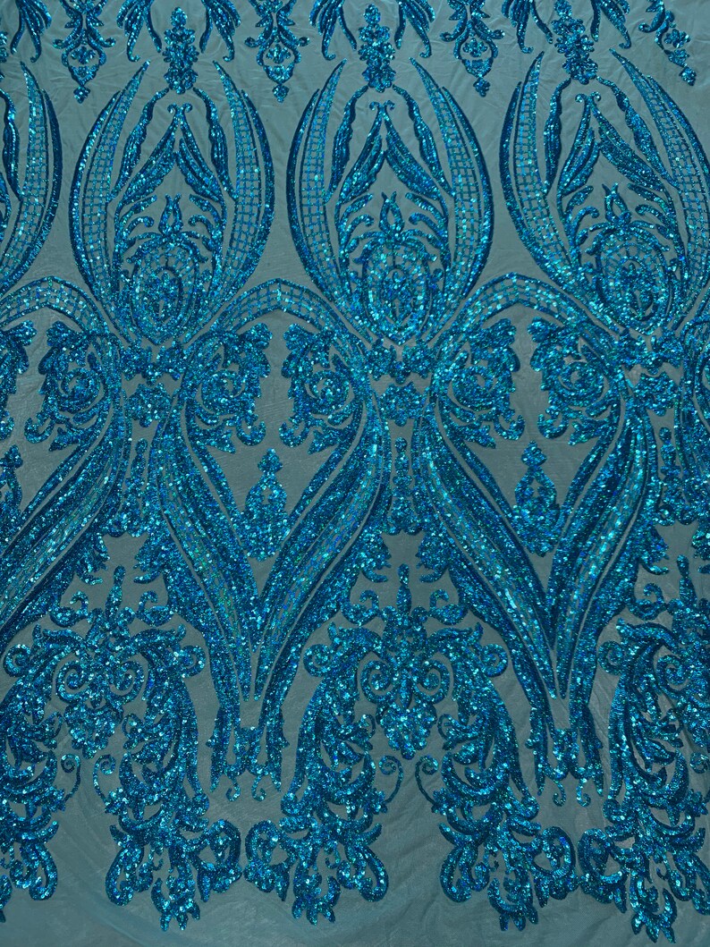 Puede incluir: Paillettes azul turquesa iridiscentes en un patr&oacute;n de damasco sobre una tela de malla transparente. Las lentejuelas est&aacute;n dispuestas en un patr&oacute;n repetitivo de remolinos y hojas.