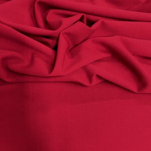 May include: A close-up shot of a vibrant red fabric with soft folds and a textured surface. The fabric is evenly lit, showcasing its rich color and subtle details. The material appears to be a medium-weight textile, suitable for various sewing projects.