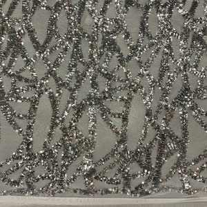 May include: Silver sequined fabric with a geometric pattern on a white mesh background.