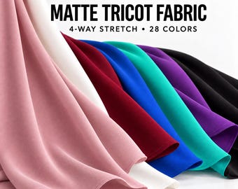 May include: Giselle matte tricot fabric with 4-way stretch in 28 colors. The image displays draped fabric in shades of dusty pink, white, burgundy, royal blue, teal, purple, and black. Text reads: GISELLE MATTE TRICOT FABRIC 4-WAY STRETCH 28 COLORS.