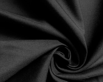 May include: Close-up of a black fabric with a smooth, textured surface. The fabric is folded and draped, creating a soft, flowing effect.