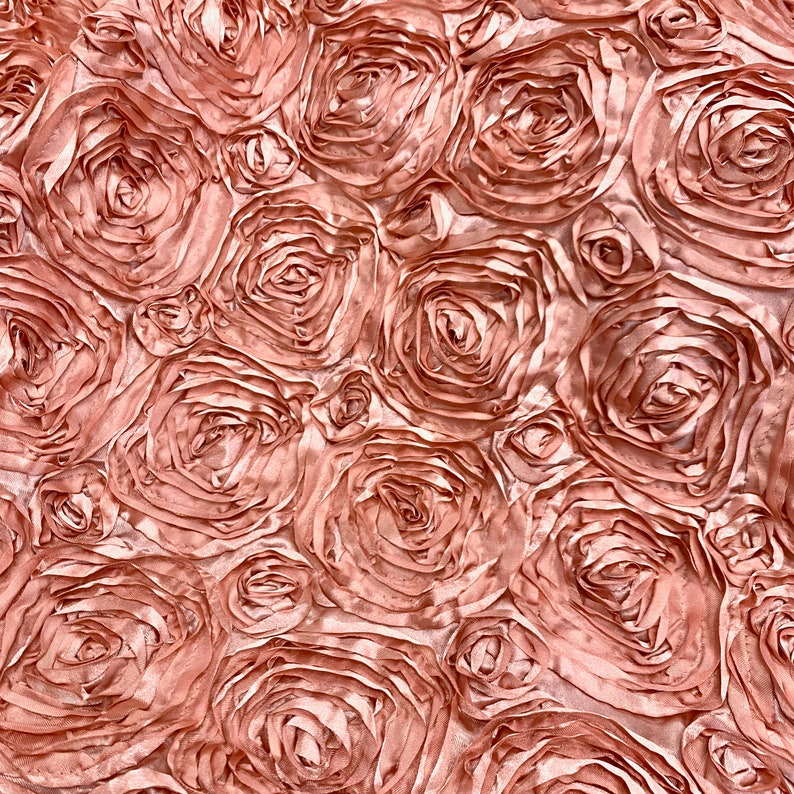 May include: A close-up of a fabric with a rose pattern. The fabric is a light pink colour and the roses are made of satin.