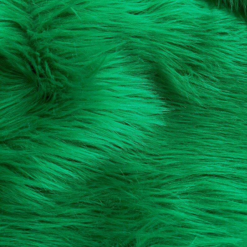 May include: A close-up of a soft, plush fabric with a deep green color. The fabric has a fuzzy texture, resembling fur.
