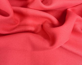 Puede incluir: Primer plano de una vibrante tela de color coral con una textura acanalada. El material está drapeado y doblado, creando sombras y reflejos suaves. La tela parece ser un material ligero, posiblemente adecuado para ropa o decoración del hogar.