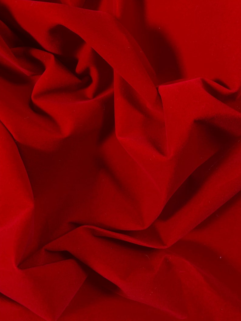 Puede incluir: Primer plano de una tela de terciopelo rojo intenso con pliegues y arrugas suaves.