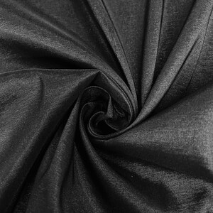 May include: Black satin fabric with a smooth, silky texture. The fabric is folded and draped, creating soft folds and curves.