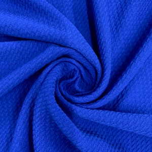 May include: A close-up of a textured blue fabric. The fabric is folded and twisted, creating a swirling pattern.