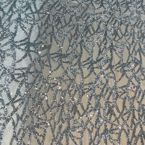 May include: Silver glitter fabric with a geometric pattern. The fabric has a mesh base and is covered in silver glitter.