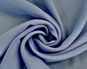 Puede incluir: Primer plano de una tela suave de color azul con una textura lisa y sedosa. La tela está drapeada y doblada, creando un patrón de remolino.