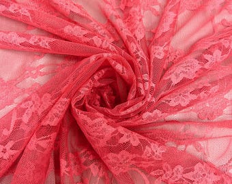 May include: Close-up of a vibrant coral-colored lace fabric. The delicate floral pattern is visible throughout the sheer material. The fabric is gathered and draped, creating a textured and layered effect. Ideal for apparel and craft projects.