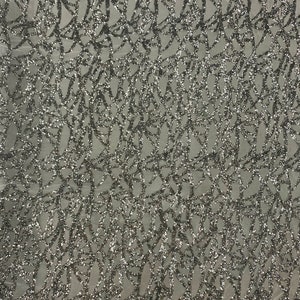 May include: Silver glitter fabric with a geometric pattern. The fabric has a mesh backing.